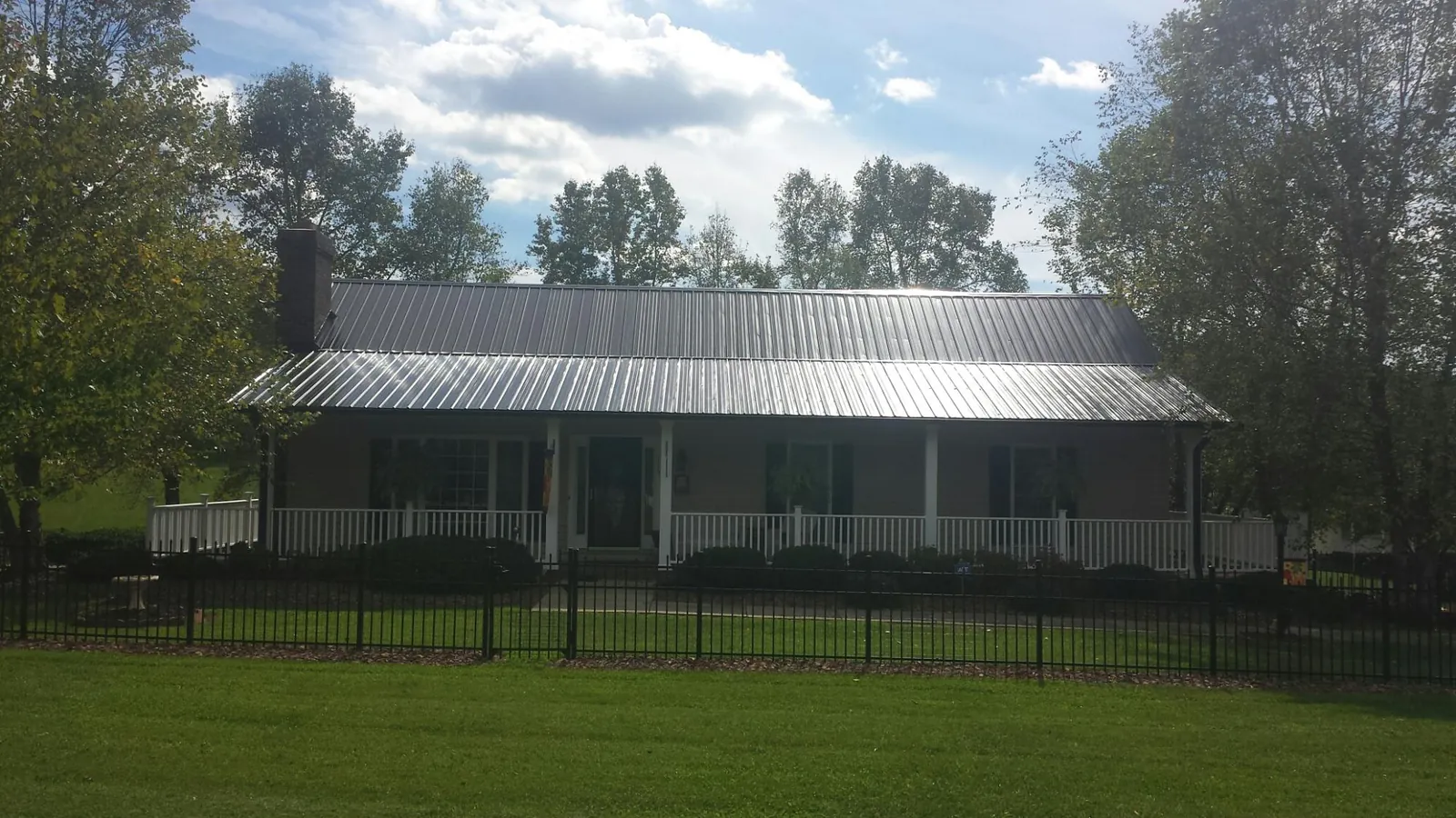 Gray metal roof on a brick ranch with a full width front porch — Gutter Guard Installation work by our crew in Dublin